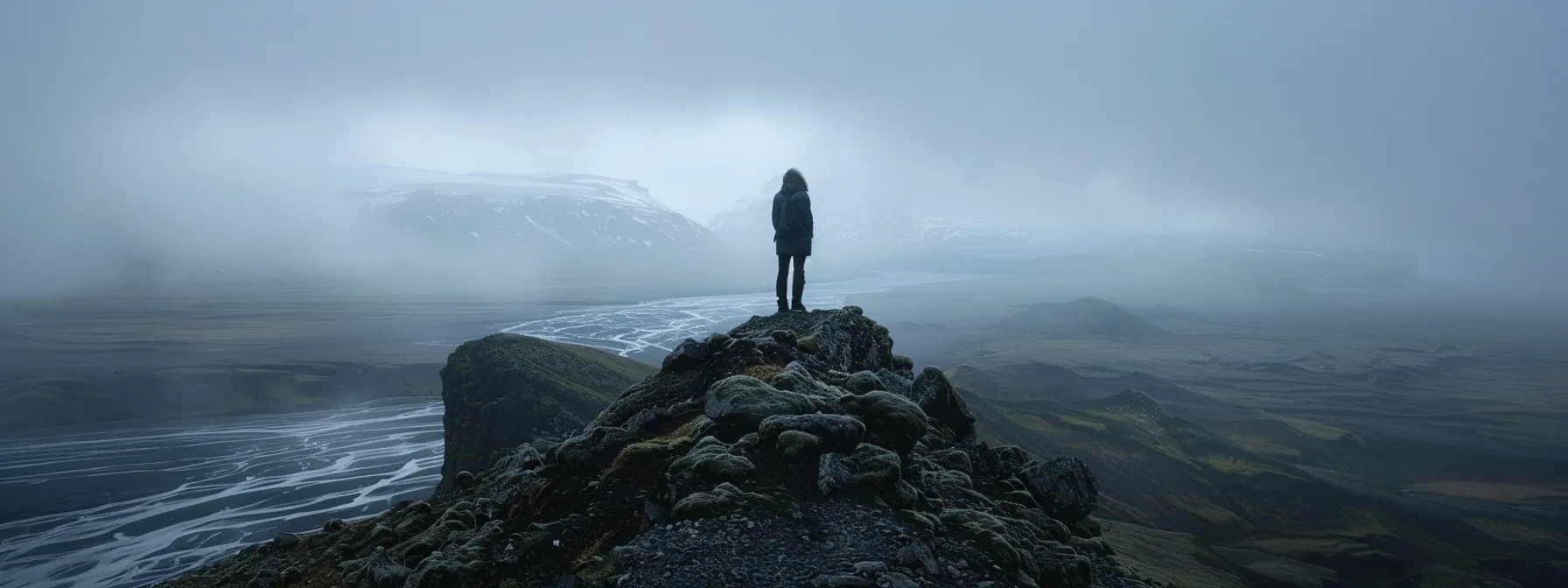 a person standing confidently at the top of a mountain, looking out at a challenging landscape, symbolizing the mindset of viewing challenges as opportunities.